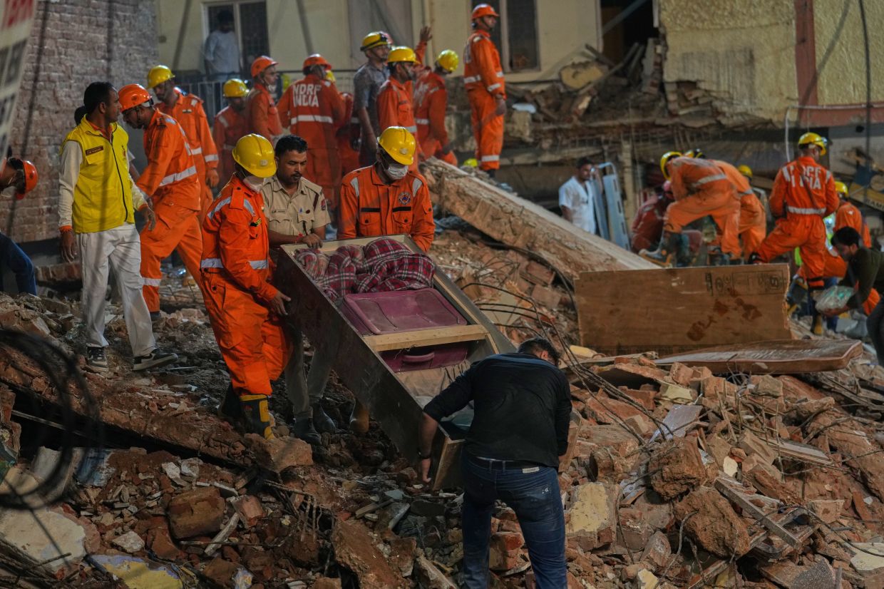 Rescue workers carry belongings recovered from the site of a collapsed building in New Delhi, India. -- AP Photo/Rajesh Kumar Singh