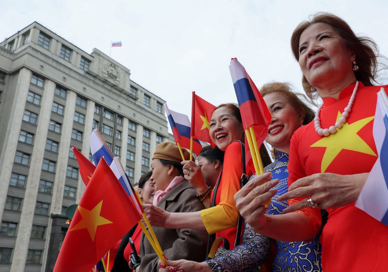 Members of the welcoming delegation hold flags in front of the headquarters of Russia's lower house of parliament, the State Duma, while waiting for To Lam, Vietnam's President and General Secretary of the Communist Party, during his visit to Moscow, Russia, on Monday, September 7, 2026. -- REUTERS/Ramil Sitdikov