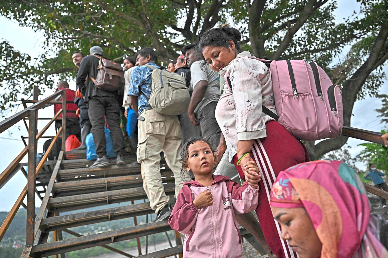 2. Locals waiting to cross the Trishuli River by zip line in the aftermath of flash floods that swept through Trishuli in Nepal’s Nuwakot district. — AFP