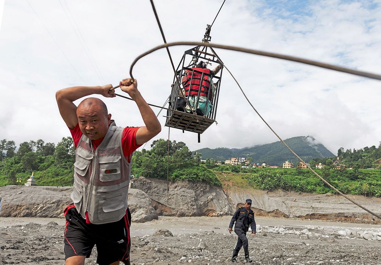 5. A worker pulling a cage carrying residents across the Trishuli River on a makeshift zip line from Koloni, after deadly flash floods damaged bridges and temporarily stranded communities. — Reuters