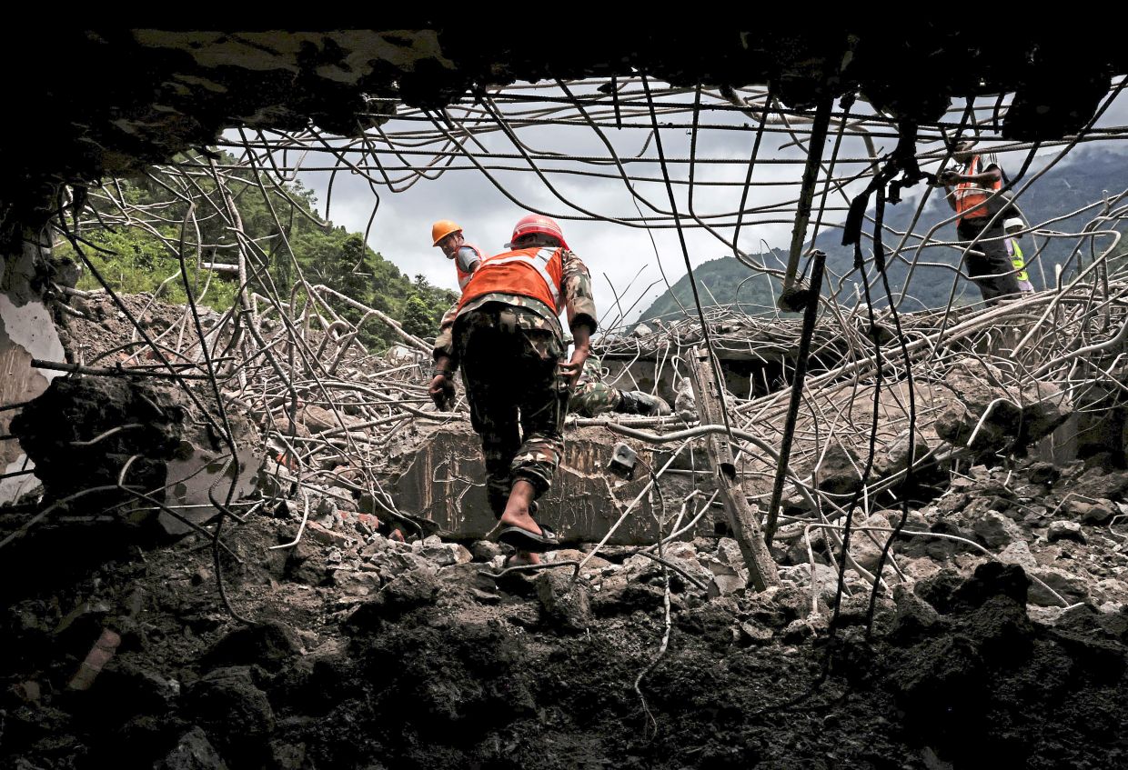 4. A member of the Nepal Army walking past a damaged building near the entrance to a tunnel at the Upper Trishuli-3A Hydropower Station. — Reuters