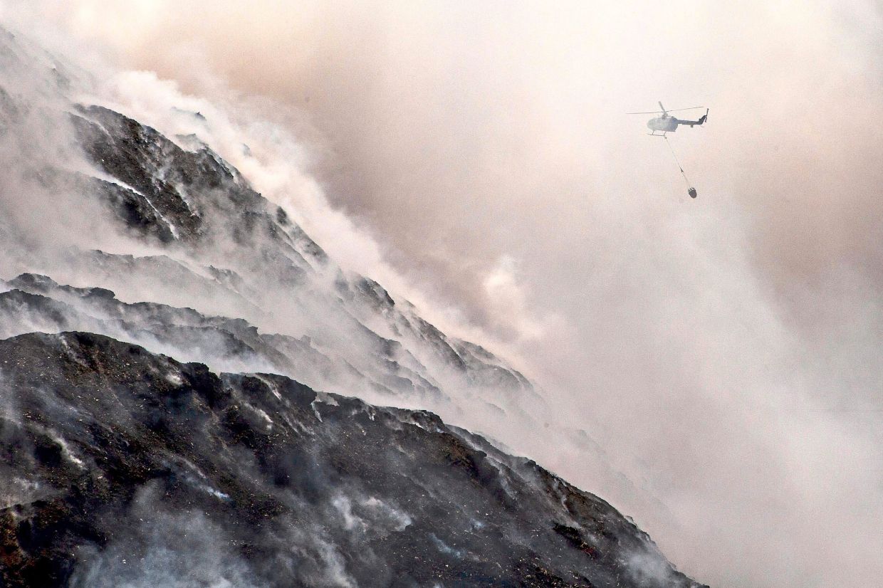 A helicopter carrying out a water-bombing operation over a fire at the Putri Cempo landfill in Solo, Central Java. — AFP