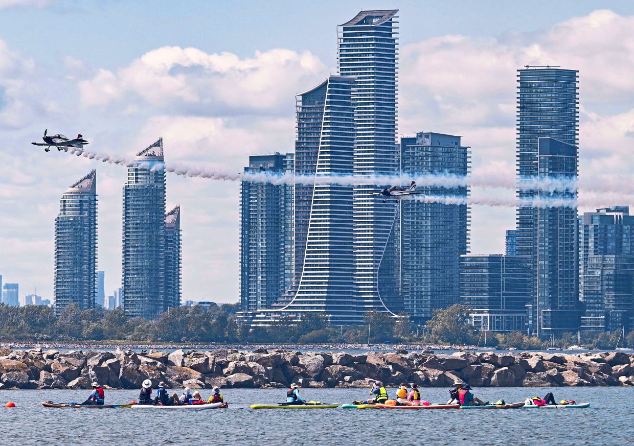 Spectators watching an aerobatic display from paddleboards on Lake Ontario during the 2026 Canadian International Air Show (CIAS) in Toronto. — Xinhua