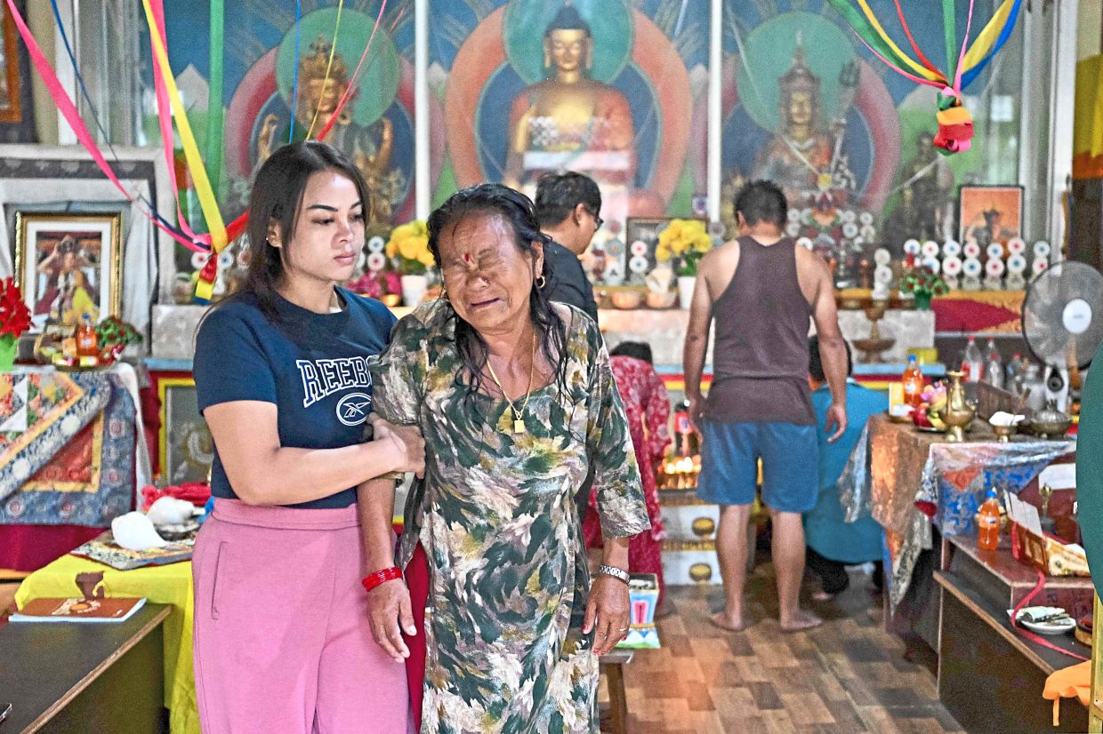 Inconsolable: Relatives of Hom Bahadur Tamang, who went missing in the flash floods, grieve as they take part in Buddhist prayers at a temple in Trishuli. — AFP