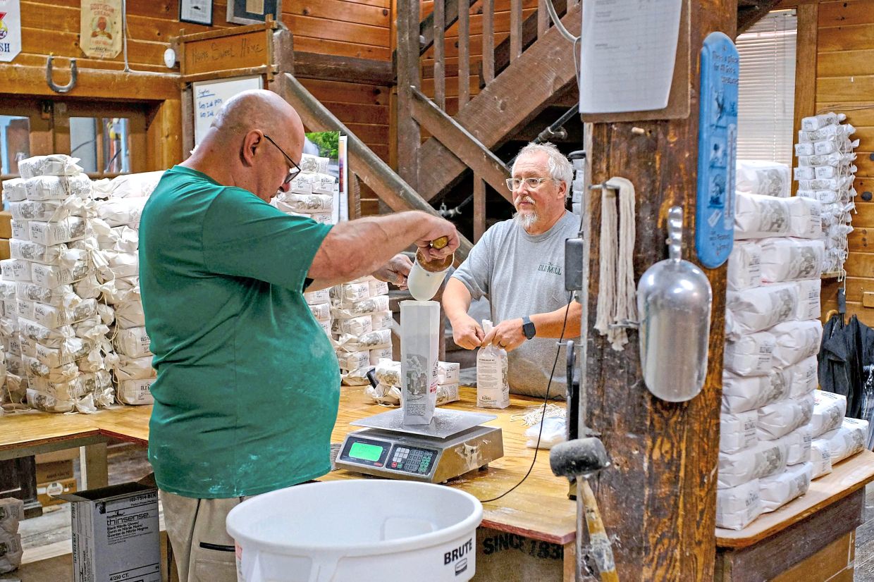 Employees at The Old Mill bagging and weighing stone-ground corn meal for customers.