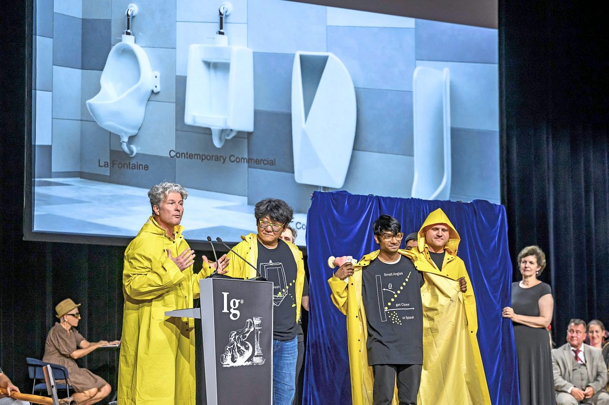Prize winners in the physics category (from left, dressed in yellow raincoats) Tadd Truscott, Zhao Pan, Kaveeshan Thurairajahand and Randy Hurd accepting their prize at the award ceremony in Zurich.