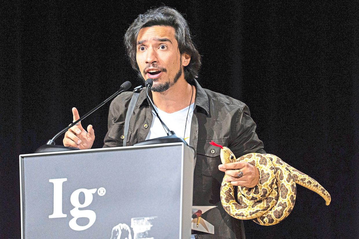 Alves-Nunes, whose team won the Ig Nobel in the biology category, making a speech at the awards with a fake snake wrapped around his arm. — AP