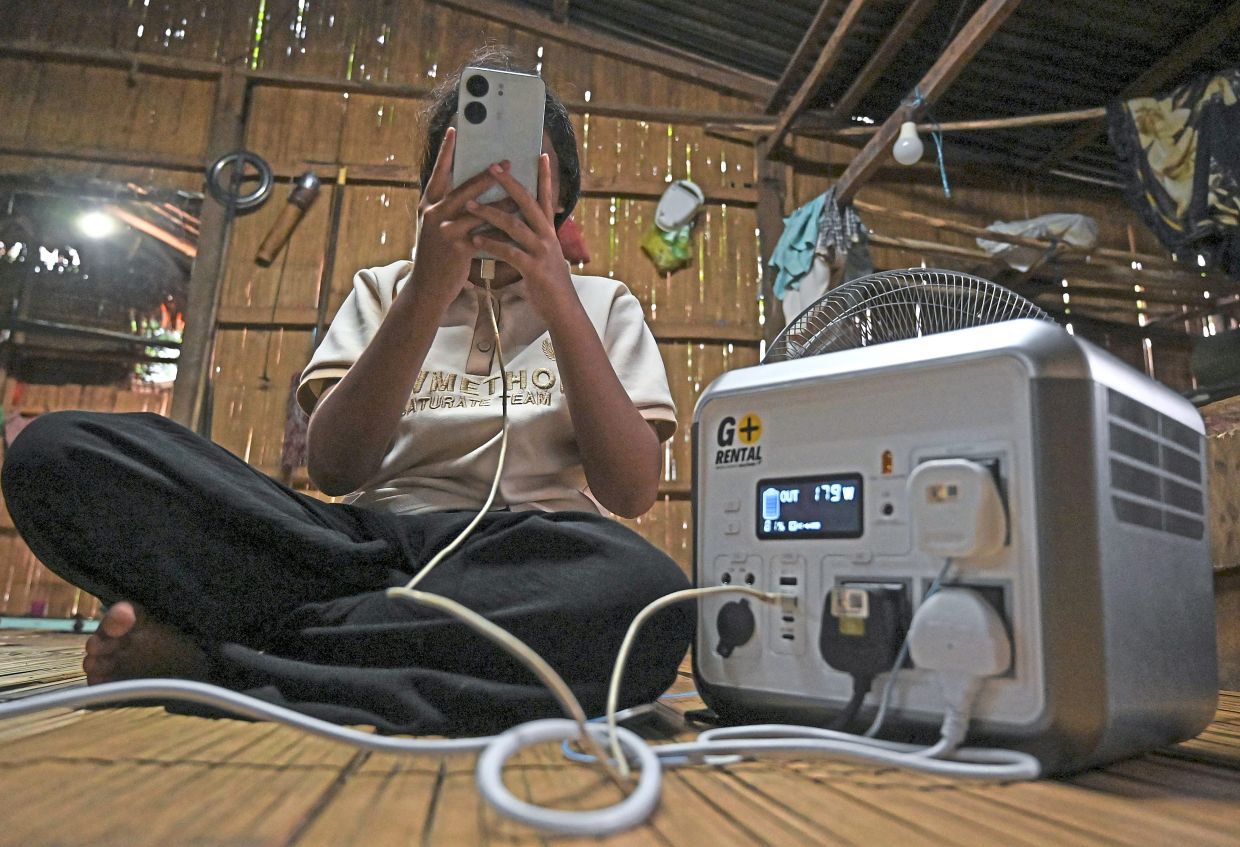 Maria Ahmad charging her phone using the portable BESS.