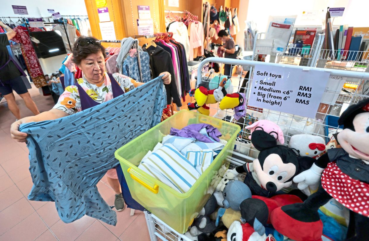 Lim sorting used clothes at WCC Value Shop in Tanjung Tokong.