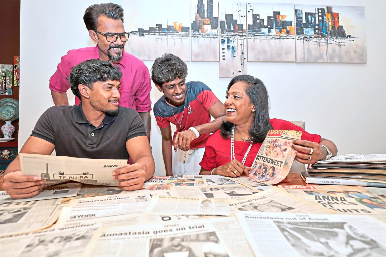 Annastasia sharing her treasured collection of ‘The Star’ newspaper cuttings with her family members (from left) Asher Joseph, Joseph Anthony and Azriel Joseph. The clippings document her journey from national racewalker to Malaysia’s first female Olympic racewalker, and the story that later opened the door to a university scholarship and a new chapter in life.