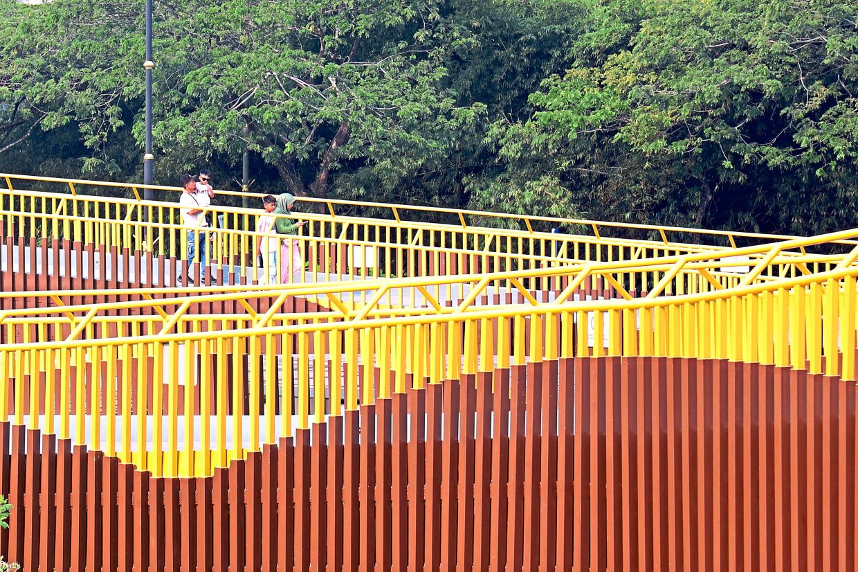 A family walking through the elevated walkway at Danga Park in Johor Baru.