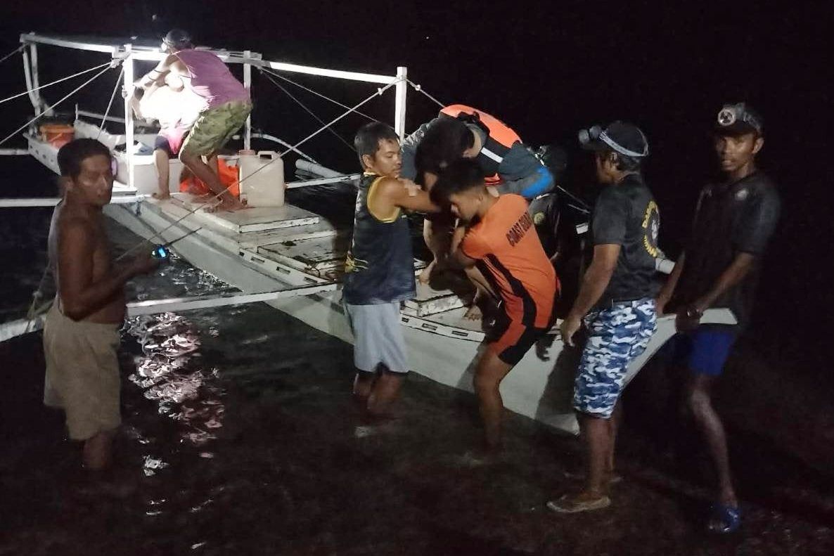 A survivor is assisted as he alights from a small boat after being rescued from the burning ferry. - Philippine Coast Guard/AP