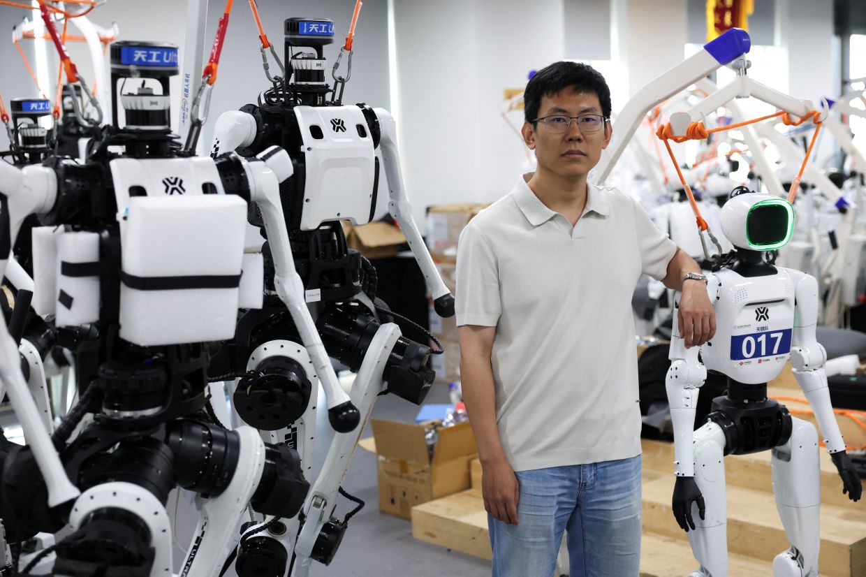 Jack Guo among Tiangong Ultra and Tiangong Omni humanoid robots at the Beijing Humanoid Robot Innovation Center. - Reuters