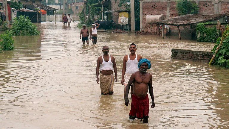 Flood-affected residents wade through floodwaters in Patna. - Photo: PTI
