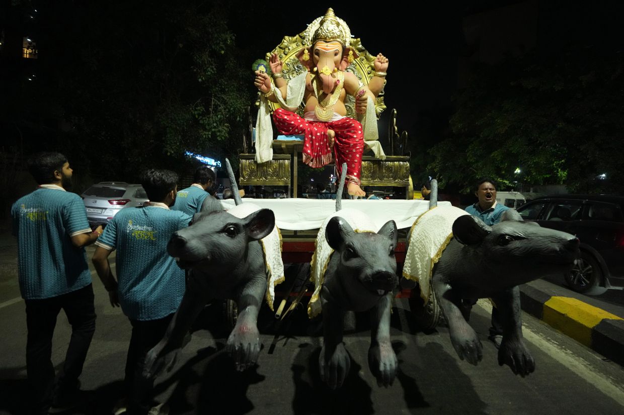 Devotees carry an idol of the elephant-headed Hindu God Ganesha to a worship venue for the upcoming Ganesha Chaturthi festival in Ahmedabad, India. -- AP Photo/Ajit Solanki
