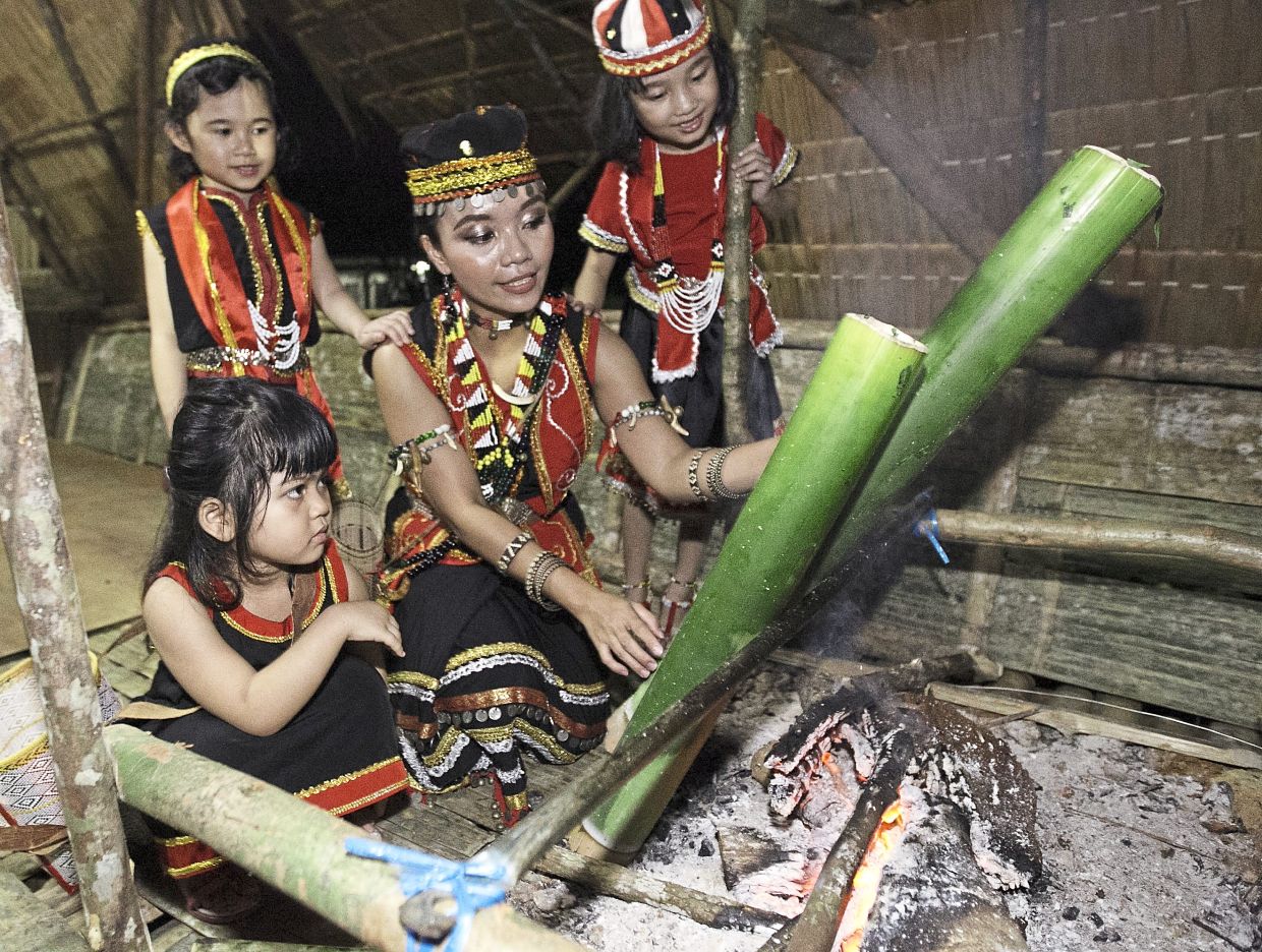 Christine Lyana teaching her nieces (from left) Averil Neysn, Marcella Kina and Mathilda Kining Durin how to cook bamboo chicken at Kampung Semaba in Kuching. Cooked with tapioca leaves, turmeric and ginger, bamboo chicken is a traditional delicacy served during the Gawai festival. — ZULAZHAR SHEBLEE/The Star/Filepic