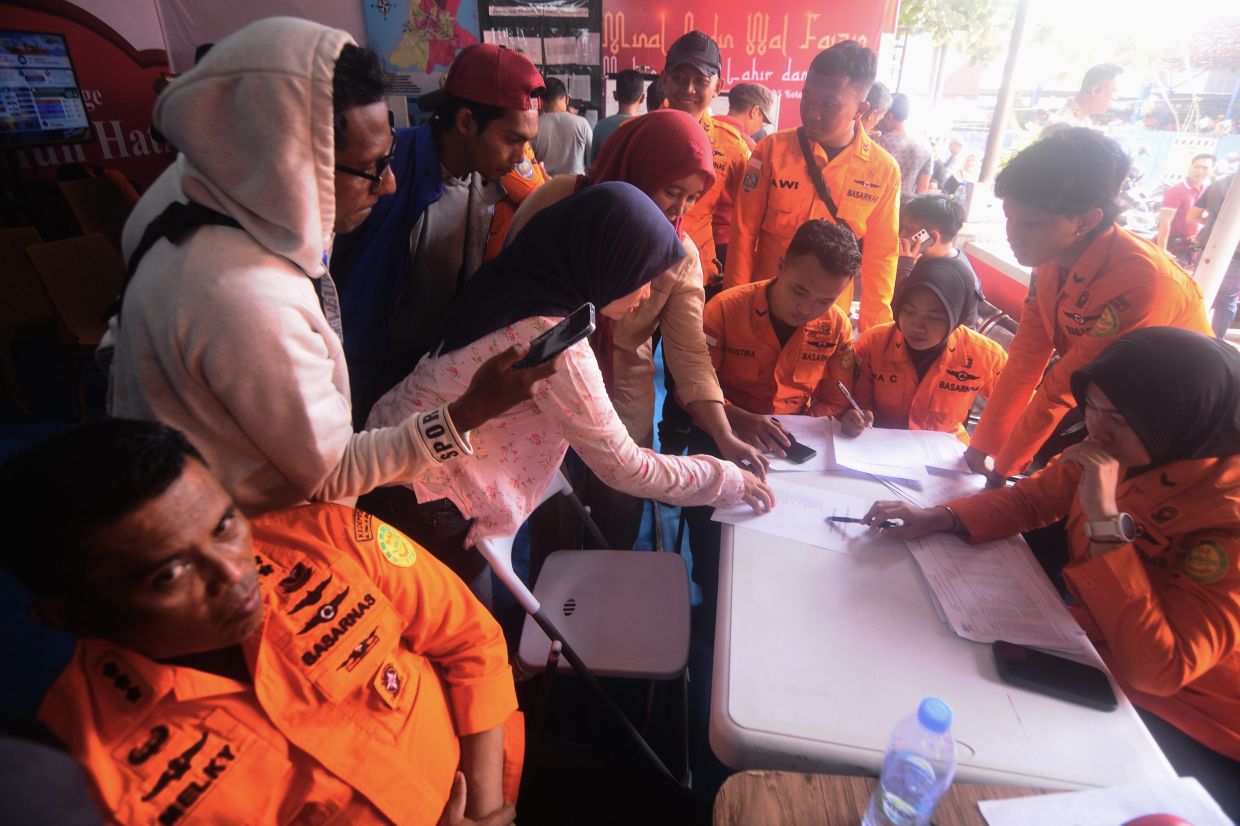People look for the names of their family members on a passenger list after a ferry overturned in bad weather in the Java Sea, at the rescuers command center in Banjarmasin, South Kalimantan, Indonesia, Sunday, Sept 13, 2026. - Photo: AP
