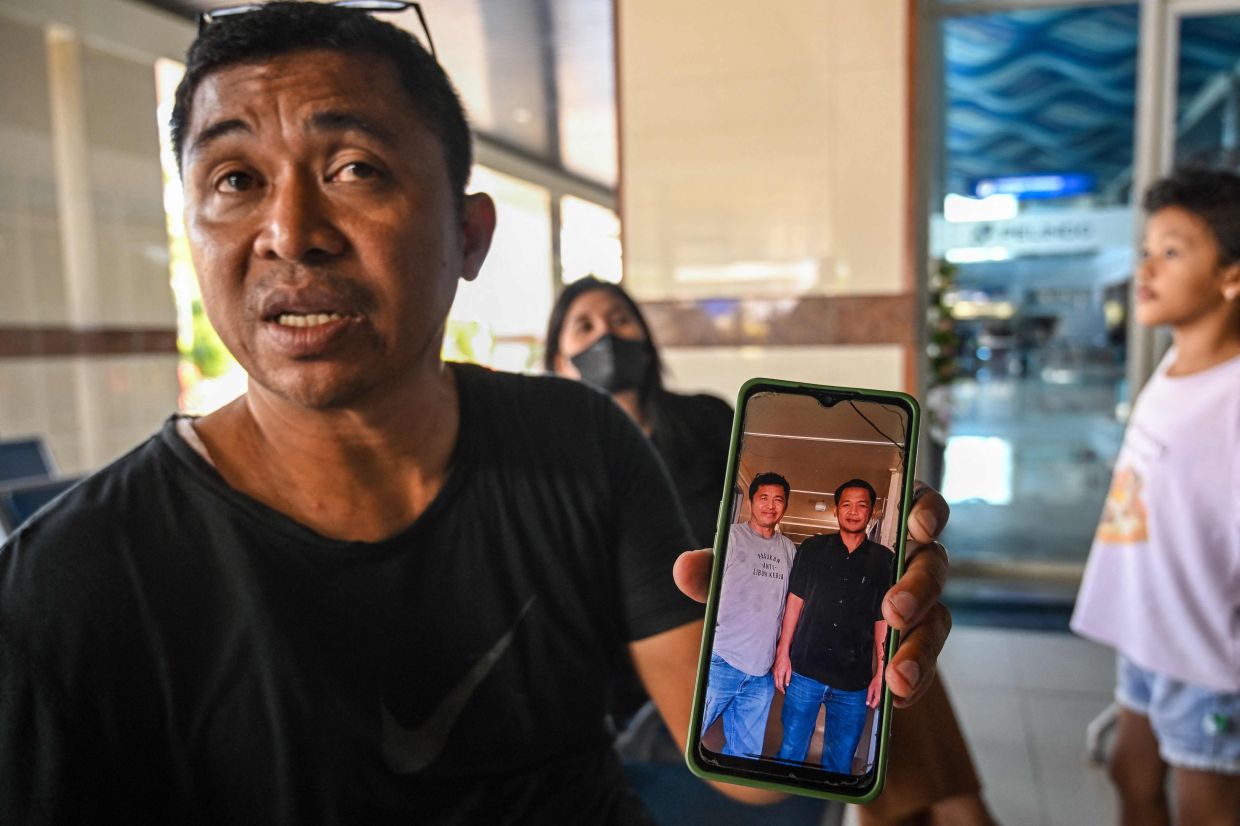 Fredy Manuhua shows a picture of his brother who was a passenger on Virgo Transport 8, carrying 243 people, which met with an accident en route from Surabaya, East Java to Banjarmasin, South Kalimantan, as relatives seek information about loved ones at Tanjung Perak Port in Surabaya on September 13, 2026. One person was killed and more than 100 were rescued on Sunday after a ferry sailing between the Indonesian islands of Java and Borneo was hit by bad weather, rescue officials said. - Photo: AFP