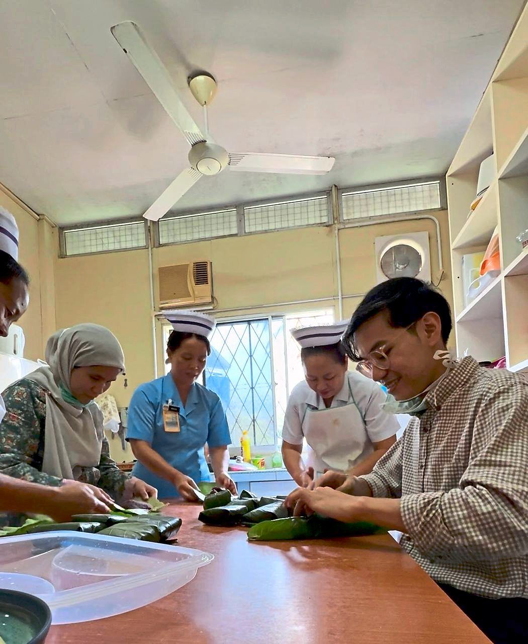 One of the ways that Dr Amirol Najmi (right) learns to cook Sabahan meals is by asking his local colleagues. — Dr AMIROL NAJMI ABDUL RASID