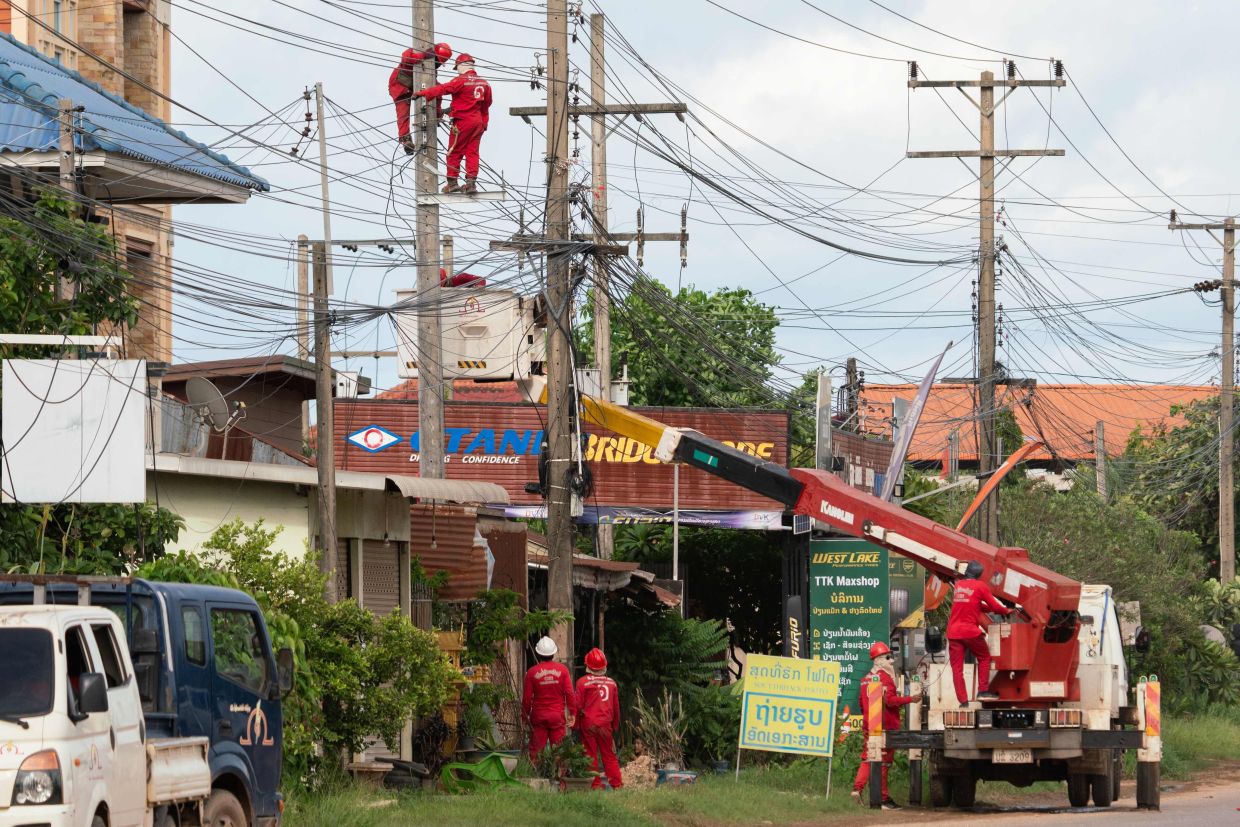 electrical technicians carry out maintenance work in the Hadxayfong district of Vientiane. -- Photo by AFP