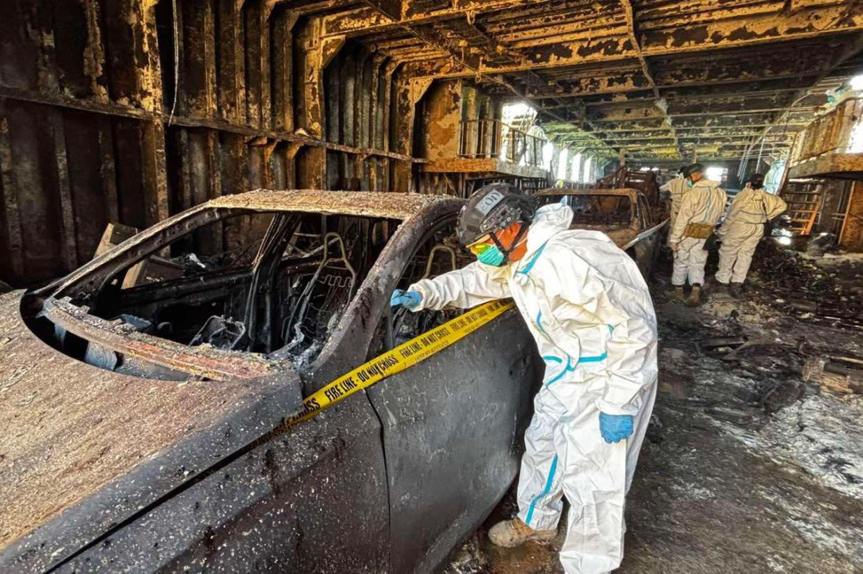 Members of the Philippine Coast Guard inspect a burned car as they continue their investigation on board the MV June Aster ferry on Monday, Sept 14, 2026, off Coron, Palawan province, western Philippines. -- Philippine Coast Guard via AP