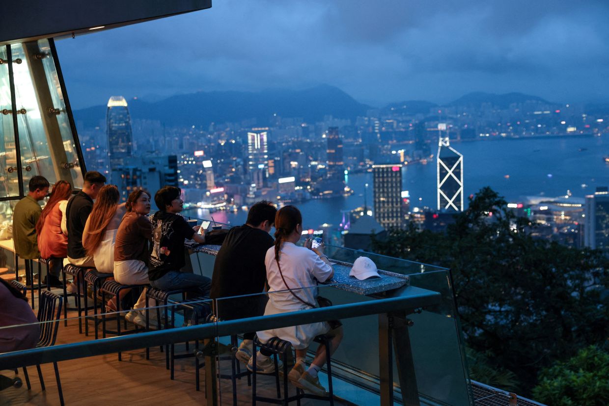 A night in Hong Kong: Tourists look at Hong Kong's skyline from The Peak Tower in Hong Kong, China. -- Photo: REUTERS/Tyrone Siu