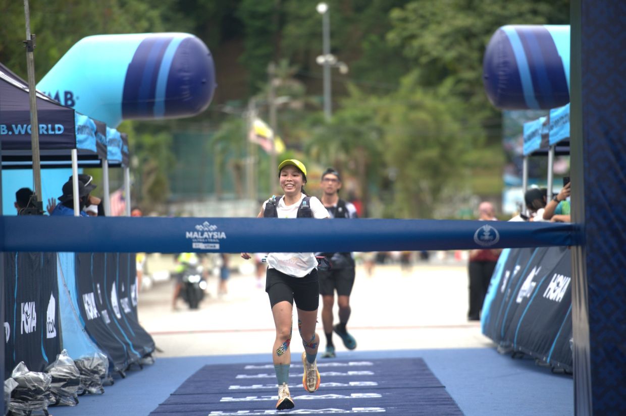 Japan’s Mika Taniguchi smiles as she holds the finishing tape after winning the women’s MY100 event.