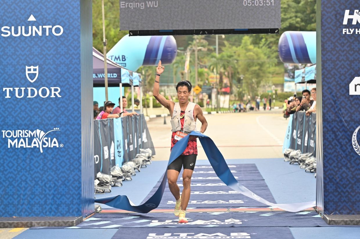 China’s Wu Erqing raises his right arm as he crosses the finish line to win the men’s MY50 event.