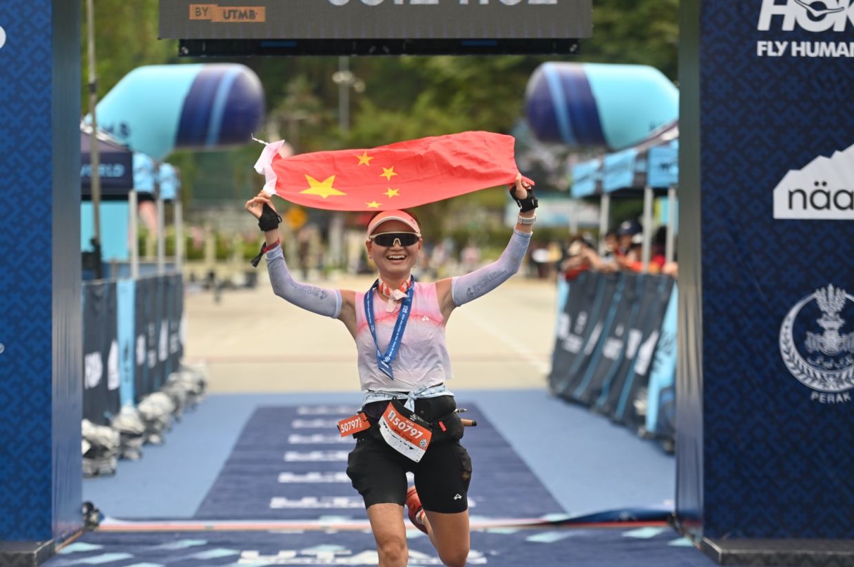 China’s Wang Dayu smiles as she holds her national flag above her head after winning the women’s MY50 event.