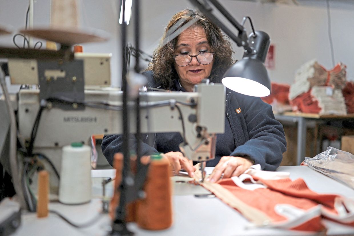 Miryan Rivas, a worker at Textil Kimba Limitada, sewing pieces of fabric to make copper vests for penguins. 