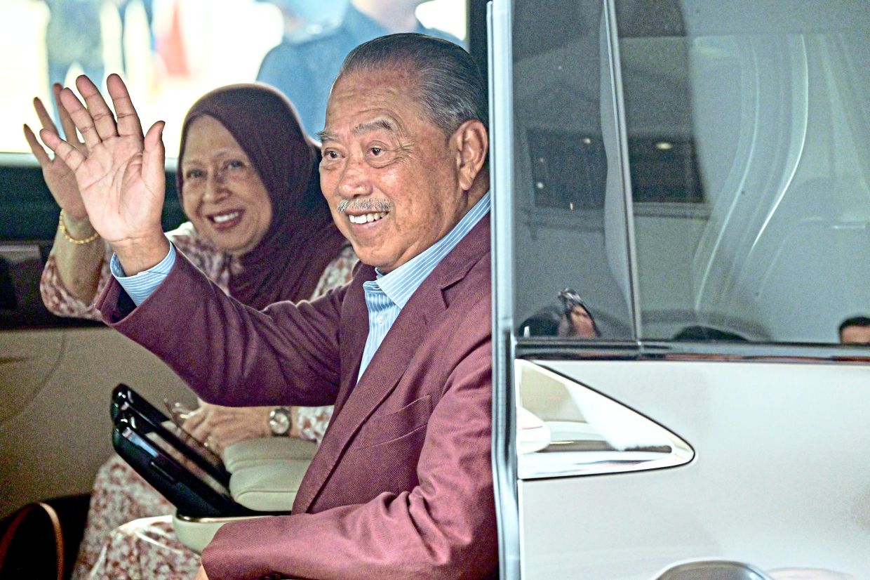 Charges dropped: Muhyiddin and his wife waving to supporters outside the Kuala Lumpur High Court. — Bernama