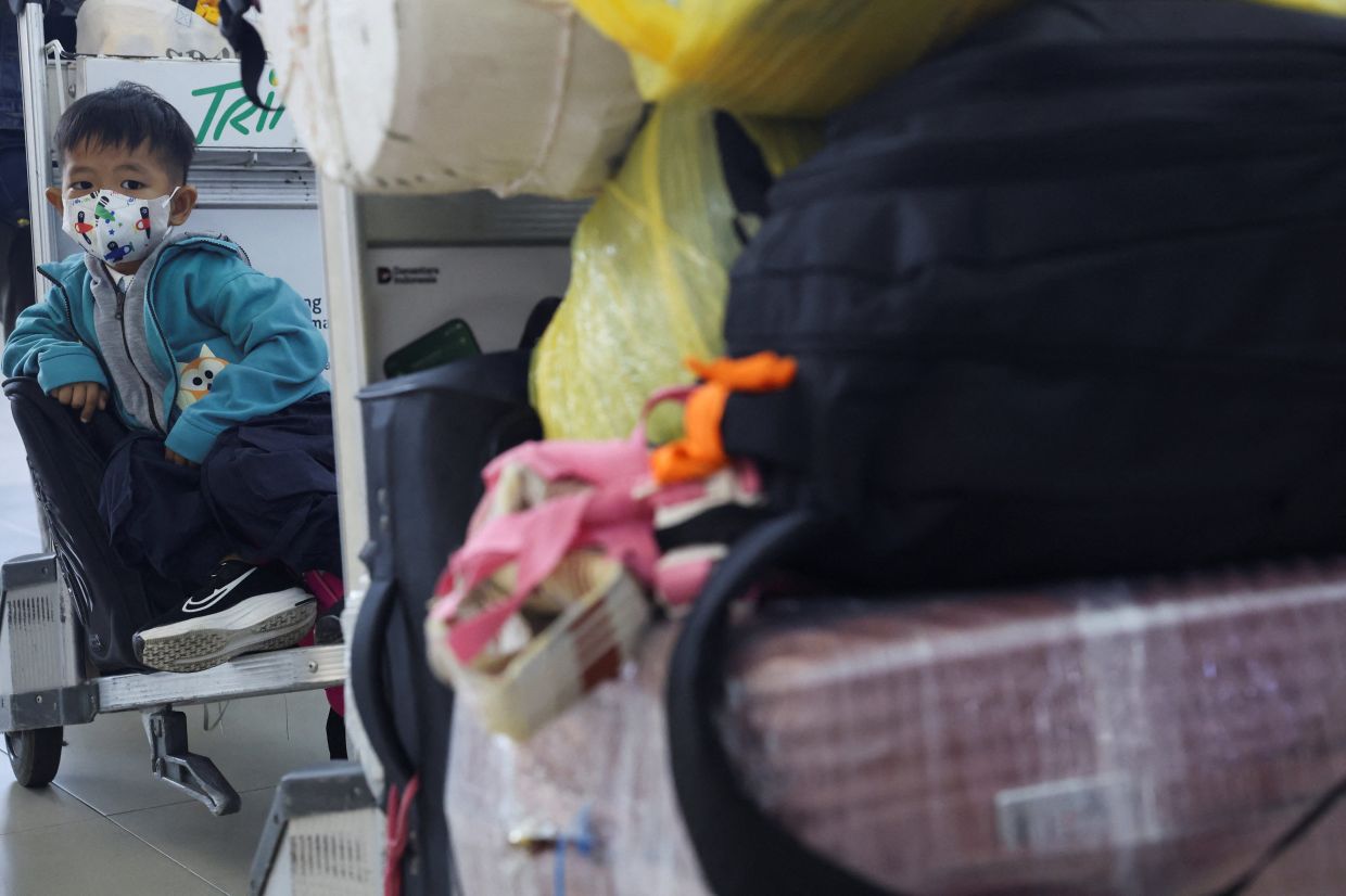 A boy wearing a protective face mask sits on a luggage trolley at Supadio International Airport, as haze from wildfires blankets the area and disrupts some flights, in Kubu Raya, West Kalimantan province, Indonesia, Sept 15, 2026. - Photo: Reuters