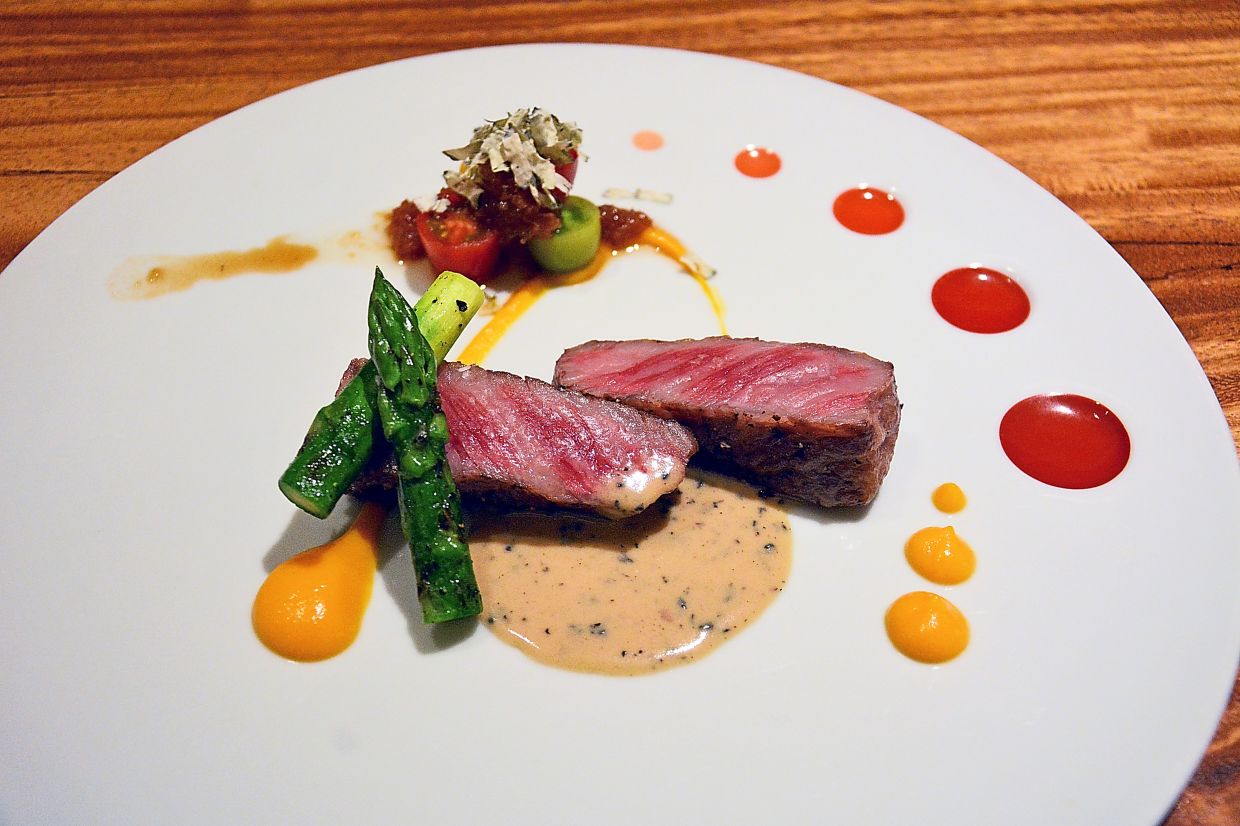 Slices of grilled A5 Wagyu on a pumpkin puree and sesame-truffle sauce, accented by heirloom tomatoes.