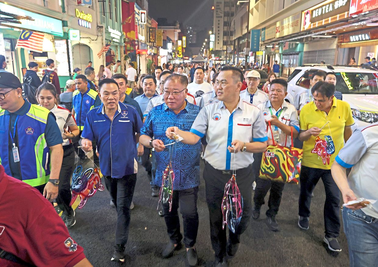 Tiong (second from left) accompanied by Petaling Street Rukun Tetangga chairman Datuk Chan Kwok Chin (third from left) and Chai (holding bag) during a walkabout in Petaling Street.