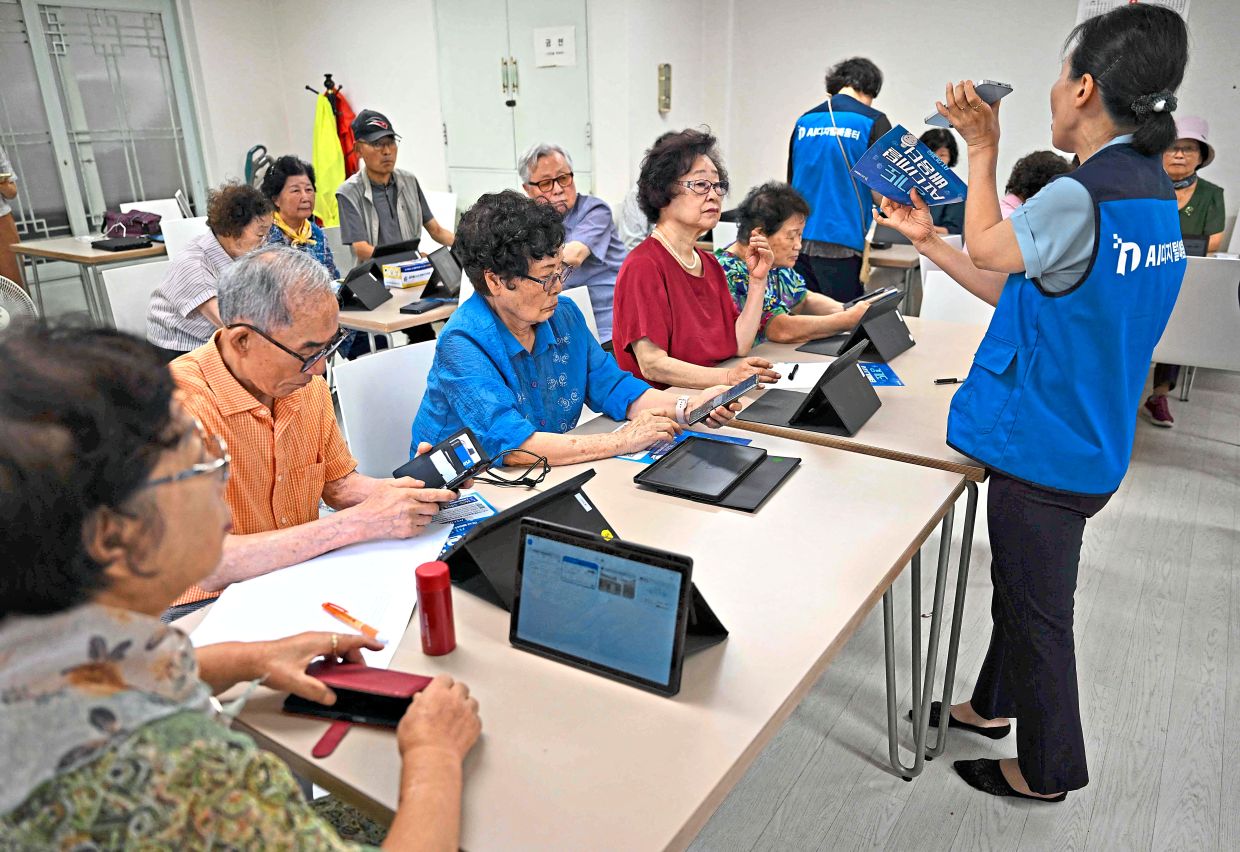 Getting connected: Elderly people using smartphones and tablet PCs during a government-organised digital survival training at a senior community centre in Suwon. — AFP