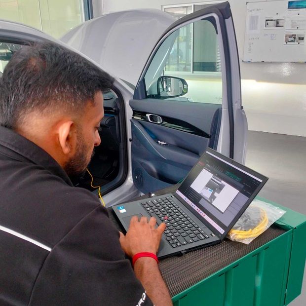 A Proton technician using a laptop computer to diagnose a Proton electrified vehicle.