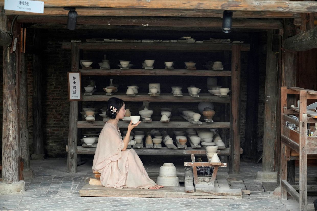 A woman wearing traditional dress sits at Taoyang alley historical and cultural tourist area in Jingdezhen.