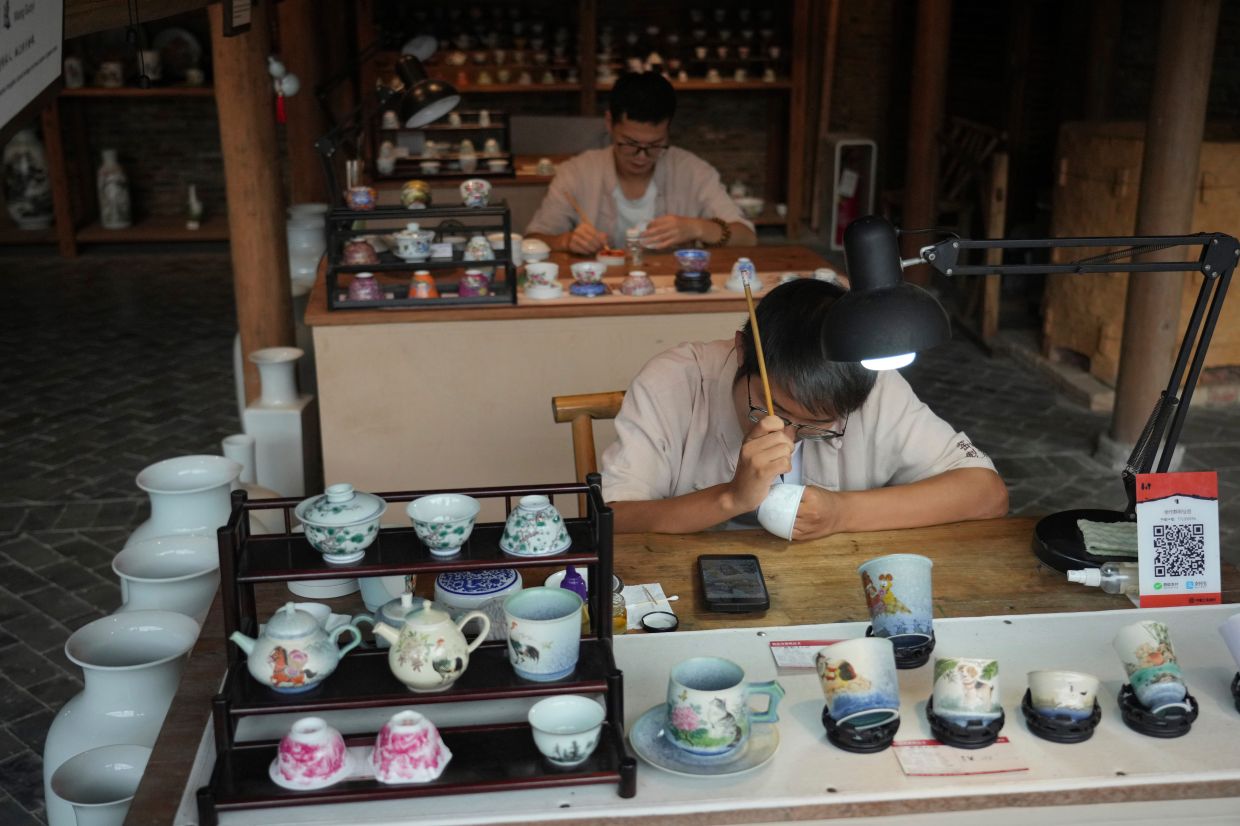A man draws on a handicrafts porcelain at Taoyang alley historical and cultural tourist area in Jingdezhen.