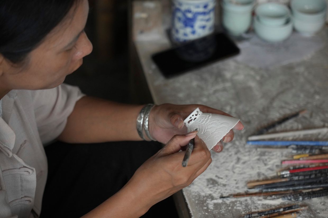 A woman decorates a handicraft porcelain at Taoyang alley historical and cultural tourist area in Jingdezhen.