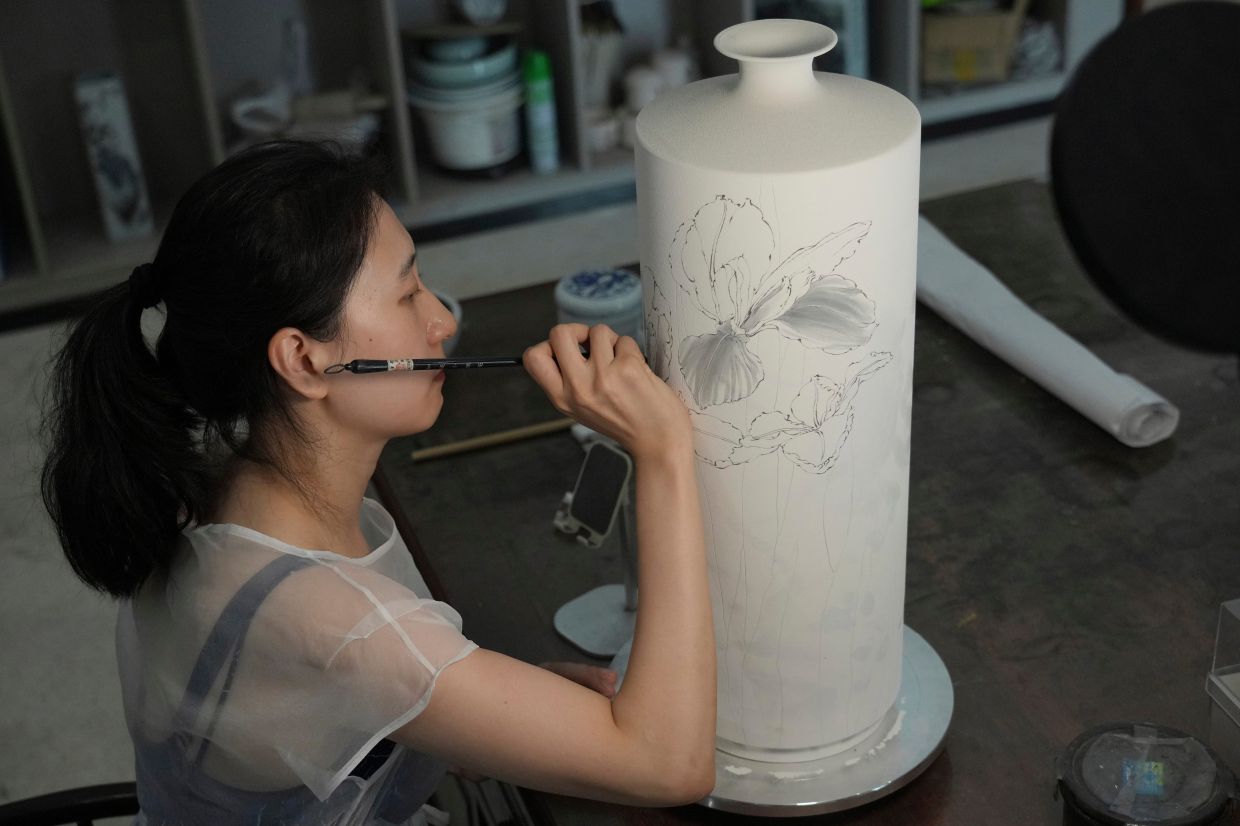 Chinese porcelain artist Chen Qing paints a vase in Jingdezhen.