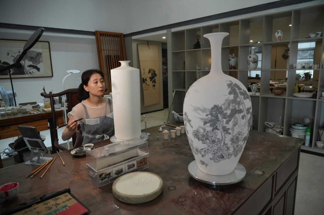 Chinese porcelain artist Chen Qing paints a vase in Jingdezhen.