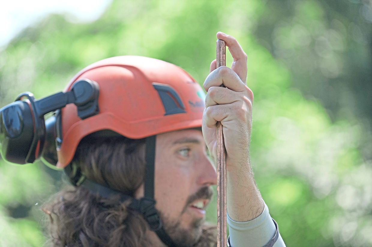 Commercial arborist Jake Love of SavATree holds a copper lightning rod next to the tree.