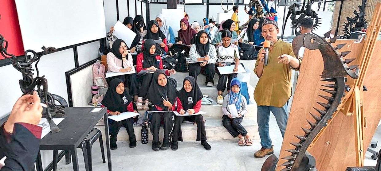 Raja Shahriman giving a talk to participating students during the Bicara Seni activity at the Merdeka Bazaar 2025 art event in Kuala Kangsar.