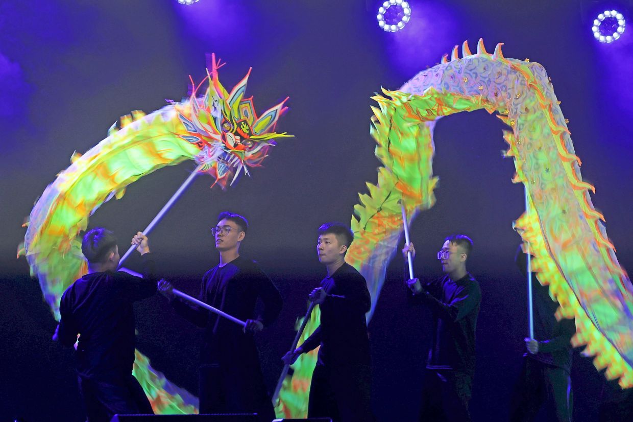 Performers skilfully manoeuvring a glowing dragon puppet on stage during the cultural showcase.