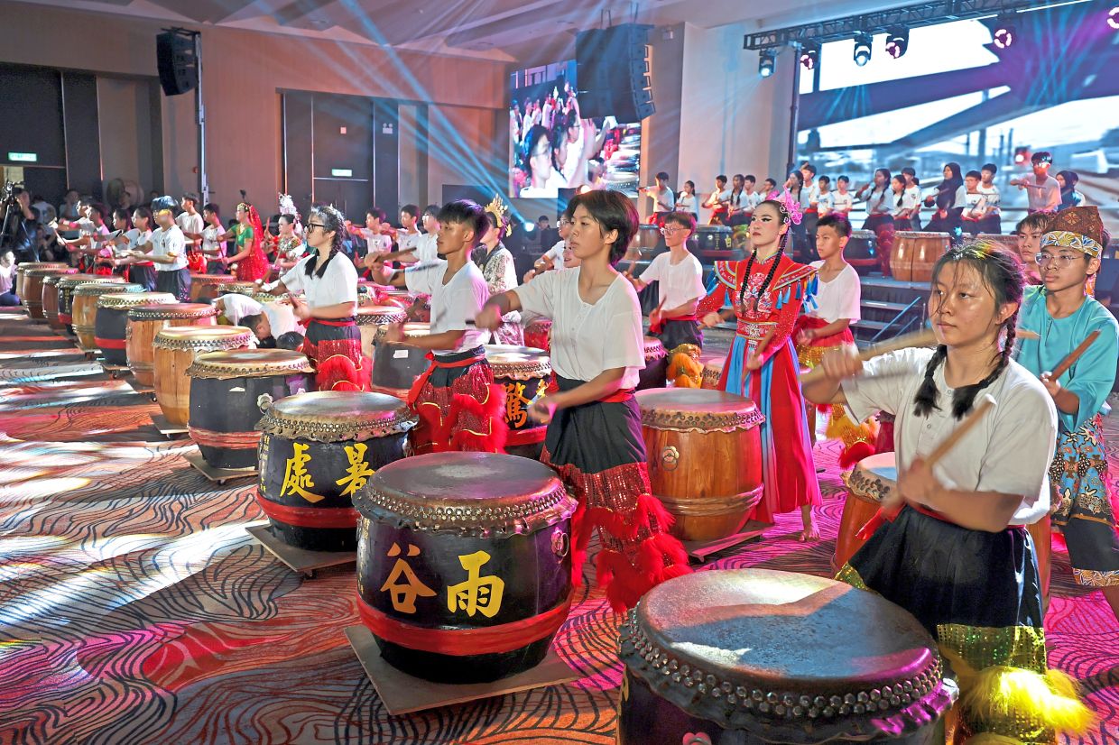 A massive ensemble of performers striking the large 24 Festive Drums in a thunderous finale.