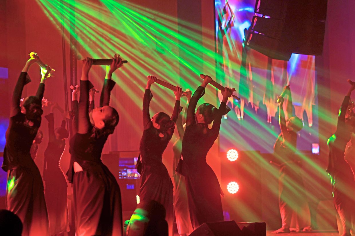 Dancers performing a captivating umbrella dance bathed in dramatic stage lighting.