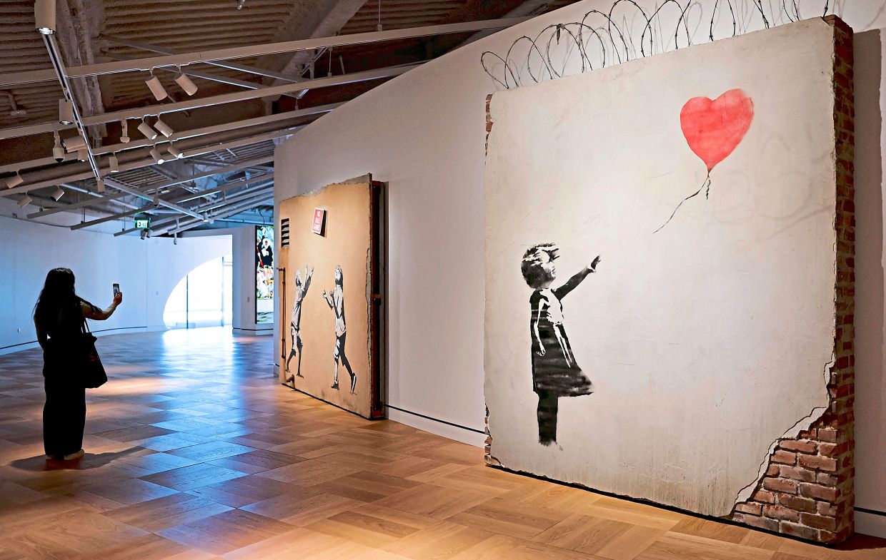 A visitor photographs a work by Banksy at the new Lucas Museum of Narrative Art in Los Angeles. Photo: AFP
