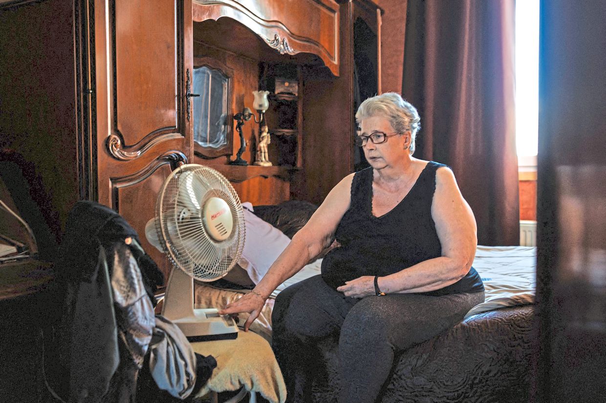 Chantal Molignier, 76, turns on the fan in a bedroom of her apartment at Place des Fetes during a hot summer day in Paris.