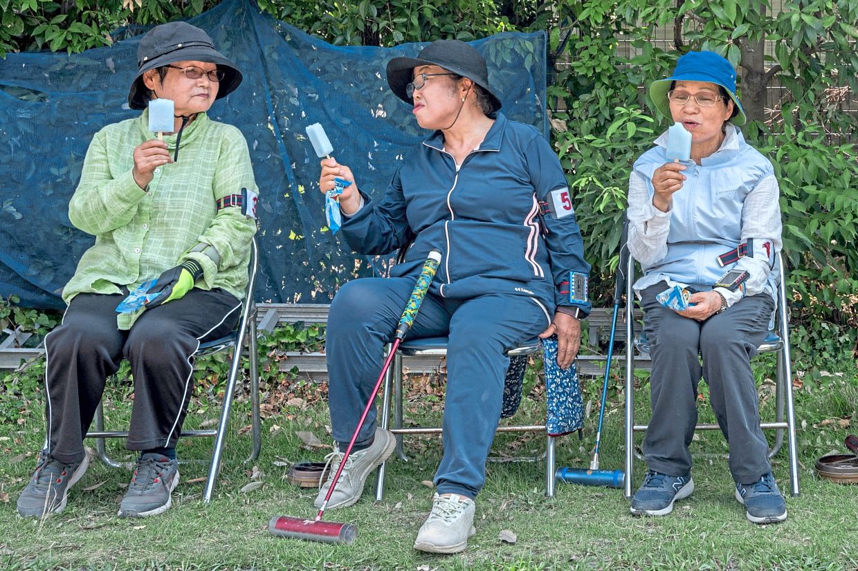 Senior citizens enjoying cool popsicles after playing the croquet-inspired game of 'gateball' at a park in suburban Tokyo.
