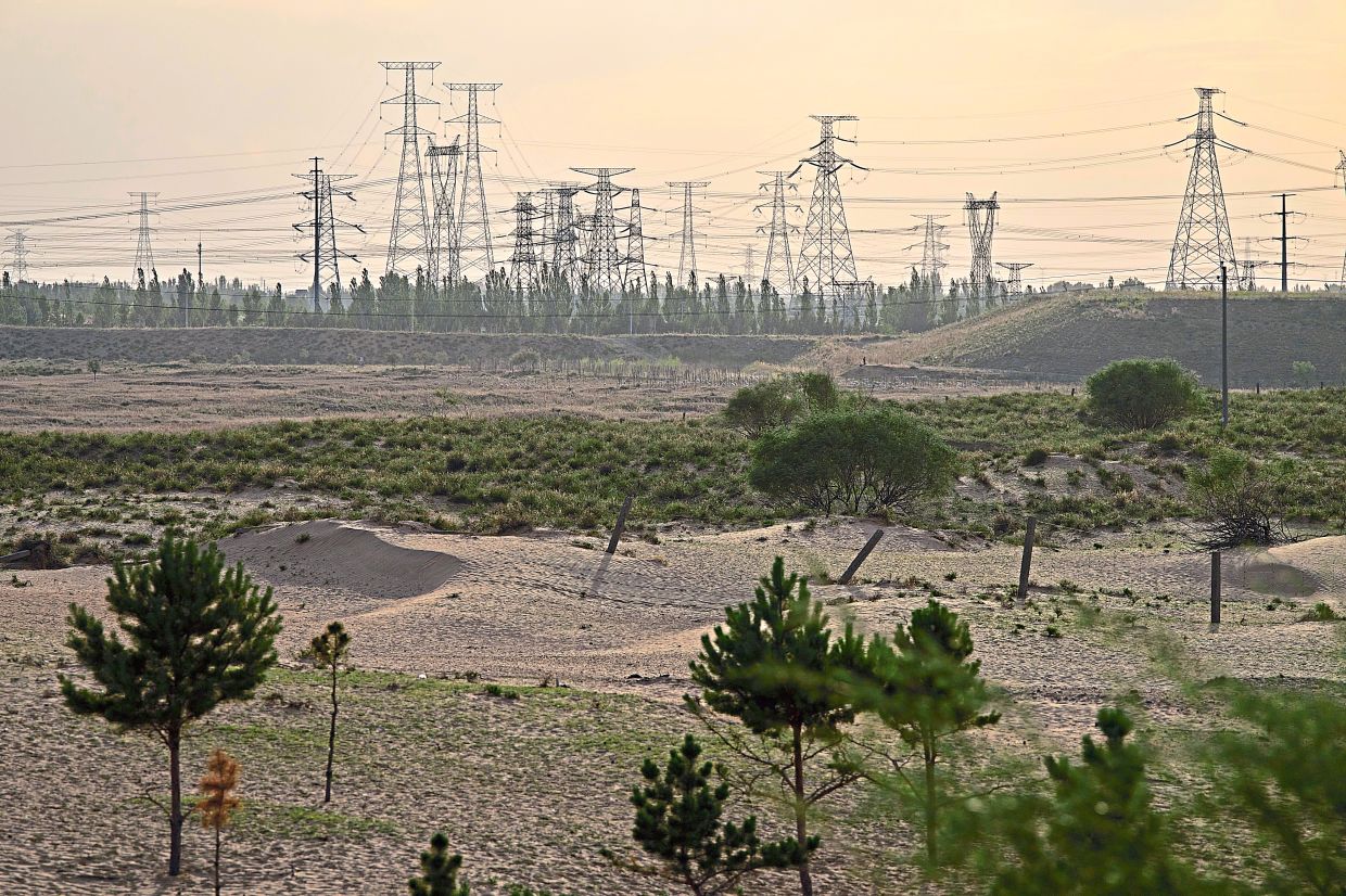 Electric pylons are seen in the horizon along sand dunes near Ordos.